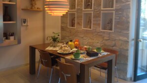 A dining area with a stone wall, a table set with plates, bowls, and a decorative lamp. - Domus Felix (Sorrento)