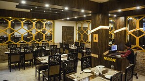 Un restaurant aux murs en bois, doté de luminaires hexagonaux et d’un comptoir avec un ordinateur.
