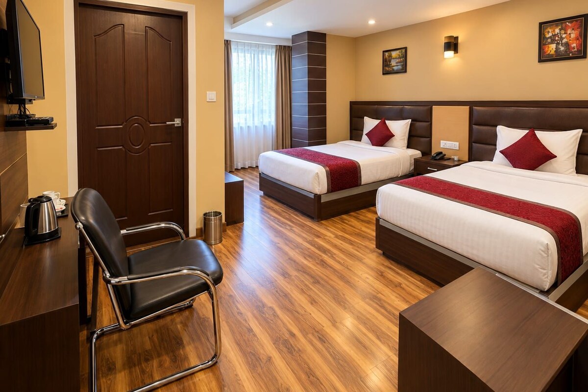 Une chambre d’hôtel avec deux lits, un bureau avec une chaise, une télévision et une fenêtre avec des rideaux.