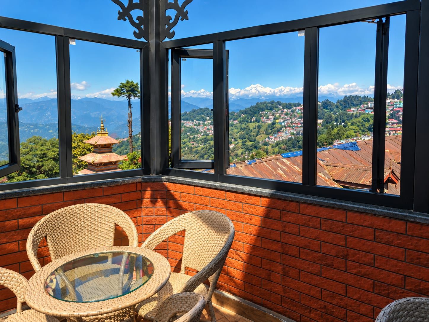 A room with a view of a mountain range, a traditional pagoda, and a village below.