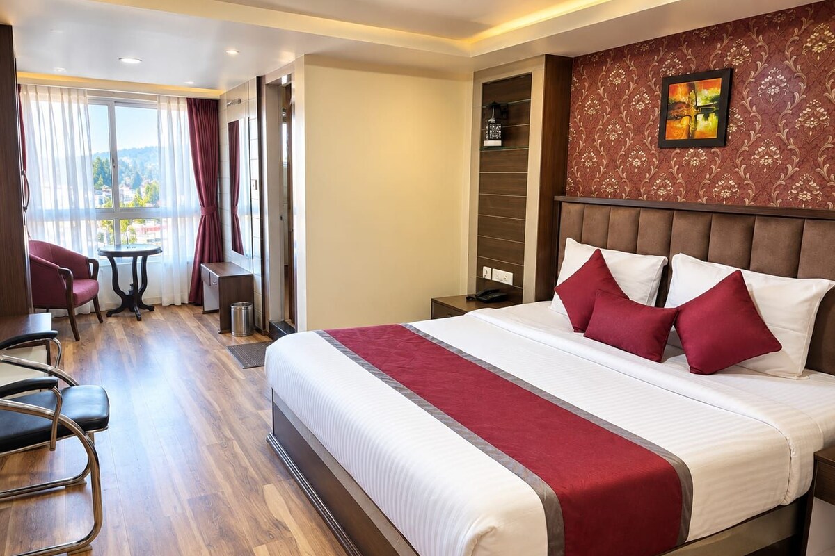 Une chambre d’hôtel avec un grand lit, un bureau, une chaise et une vue sur l’extérieur.
