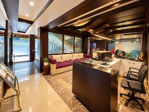 A reception area with a sofa, a desk with chairs, a large window, and a staircase.