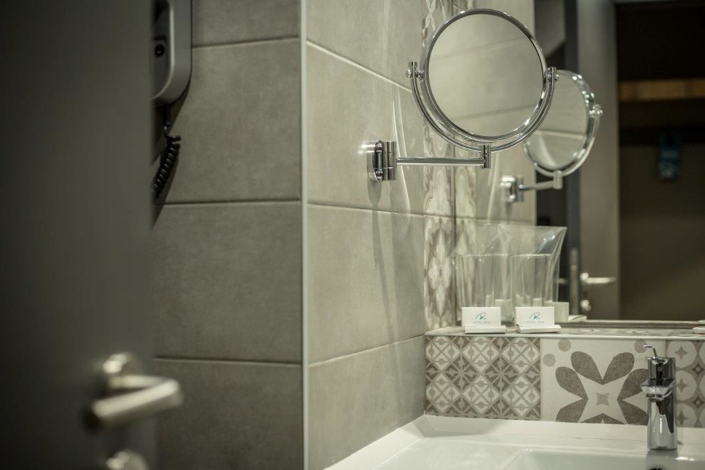 A bathroom with a sink, mirror, and towel rack.