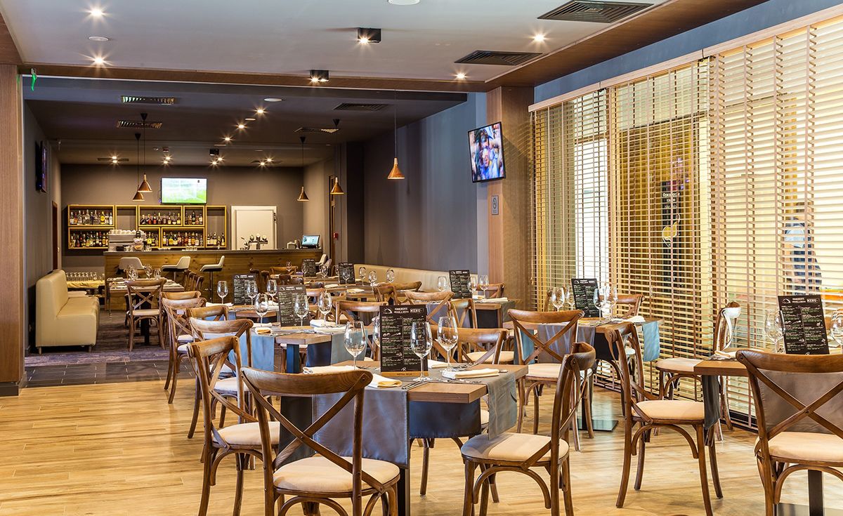 Un restaurant avec des meubles en bois, un coin bar et un écran de télévision.