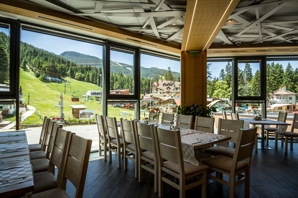 Un restaurant doté de grandes fenêtres donnant sur un paysage montagneux.