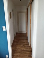 Um corredor com piso de madeira e paredes brancas.