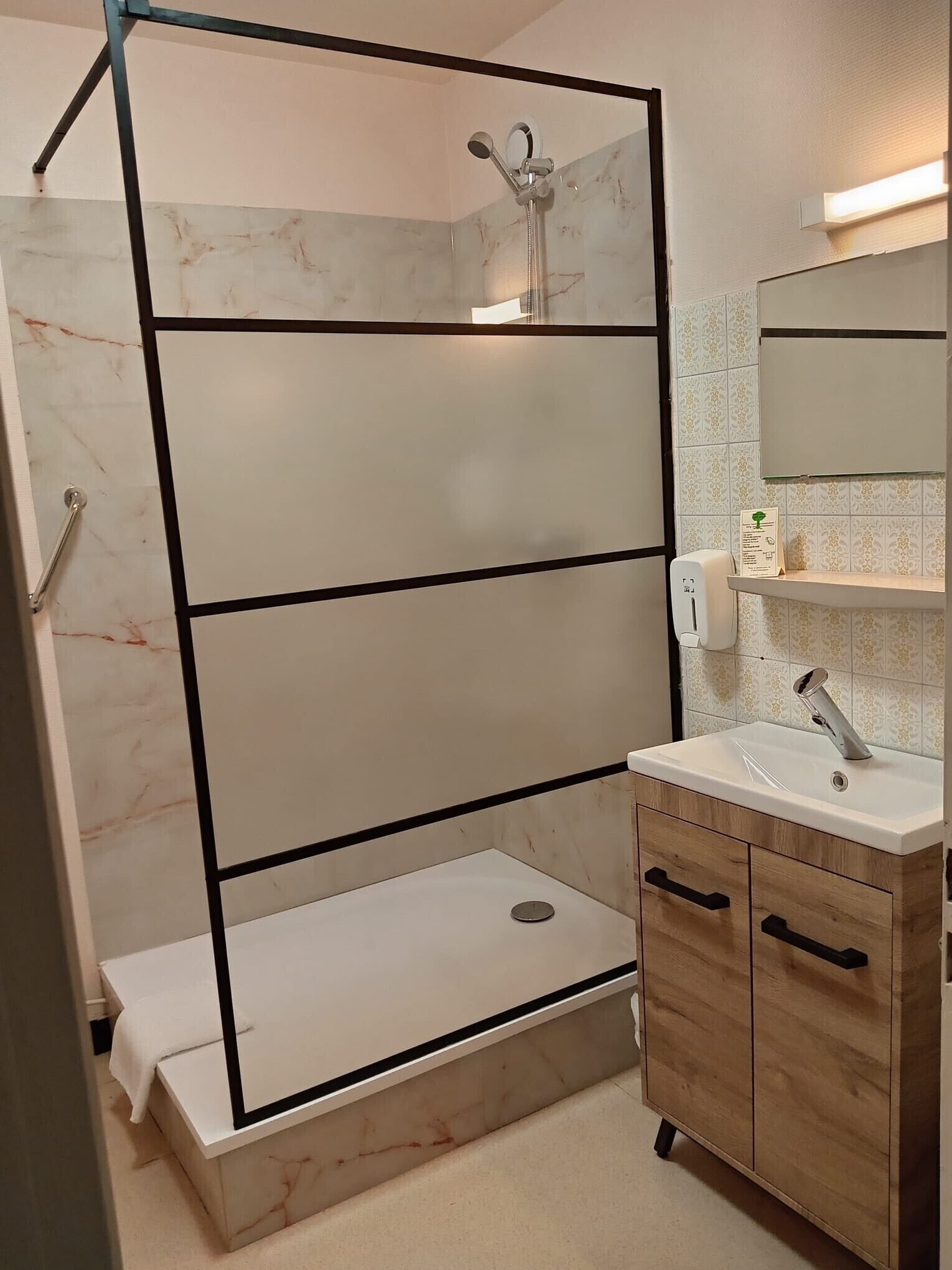 A modern bathroom with a glass shower enclosure, a sink with a mirror, and a wooden cabinet.