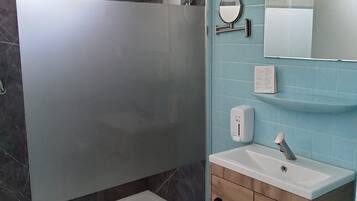 A modern bathroom with a glass-enclosed shower, a sink with a mirror, and a vanity with a soap dispenser.