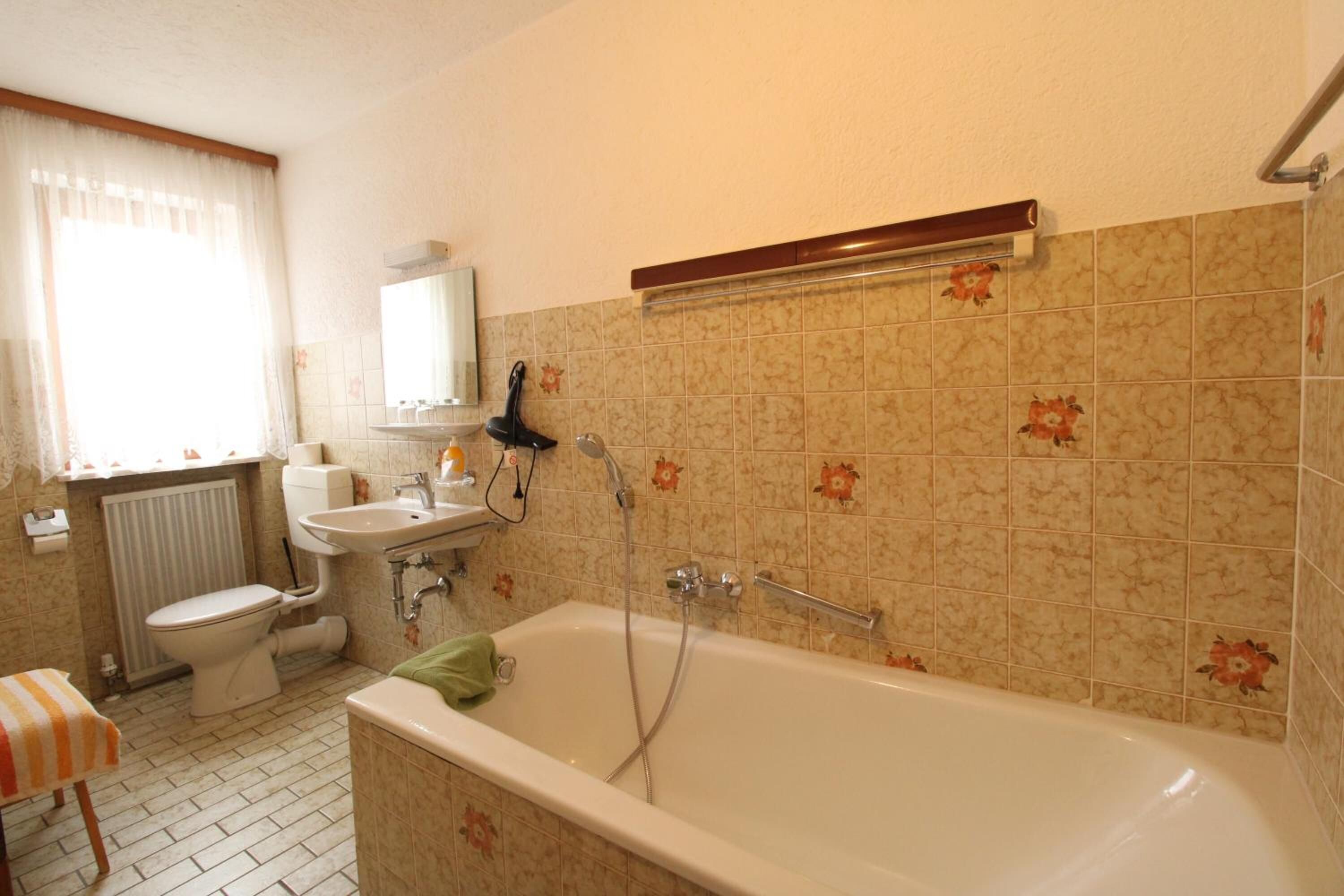 Un baño con bañera, inodoro, lavabo y un espejo sobre el lavabo.