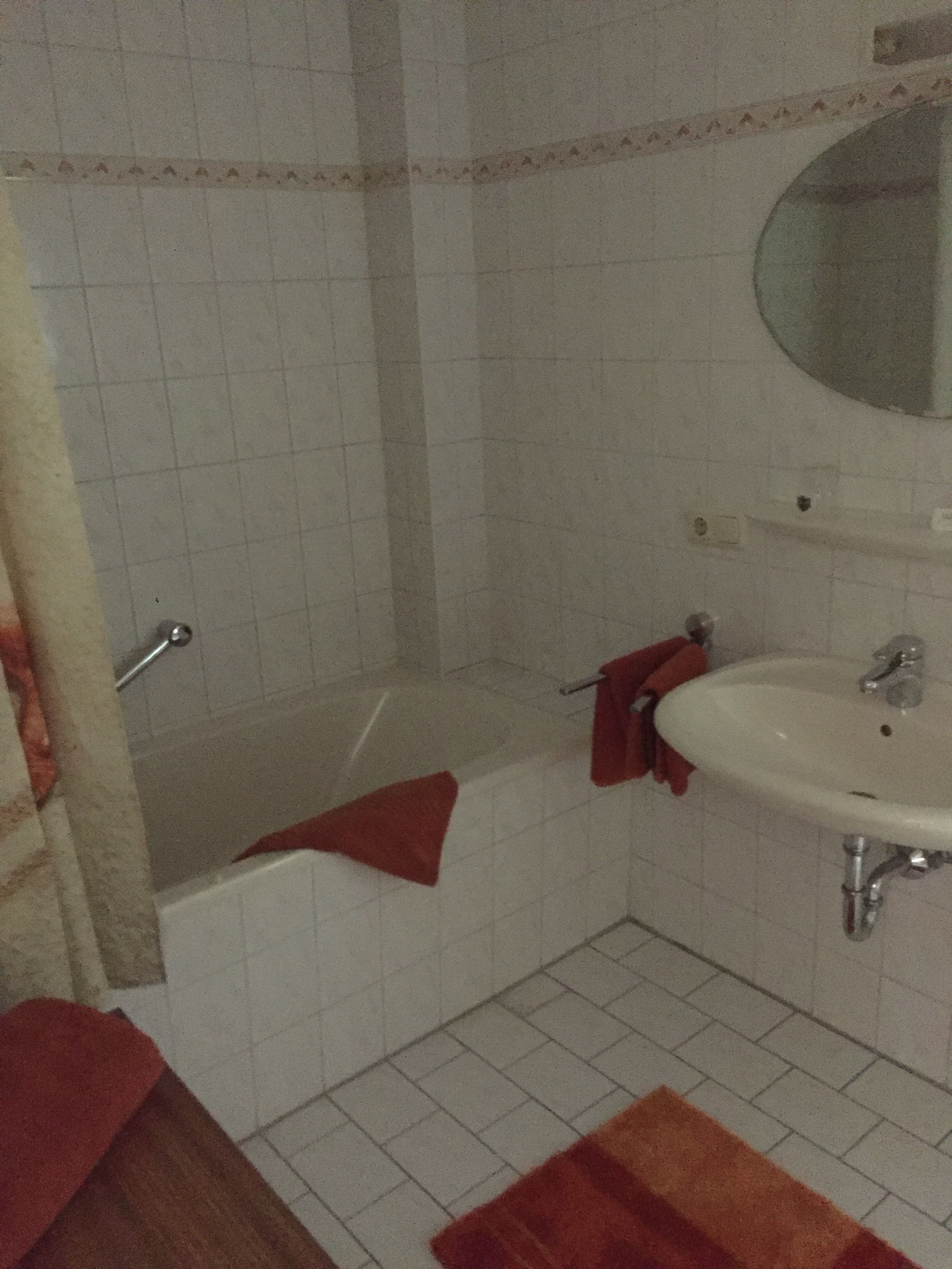 A bathroom with a bathtub, a sink, and a mirror.