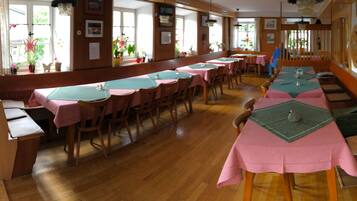 A dining area with long tables covered in pink tablecloths, wooden chairs, and benches.
