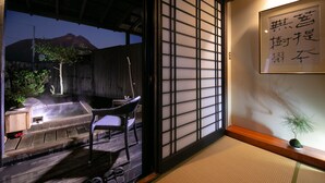 Una habitación japonesa tradicional con suelo de tatami, una mesa baja, una silla y un biombó shoji.