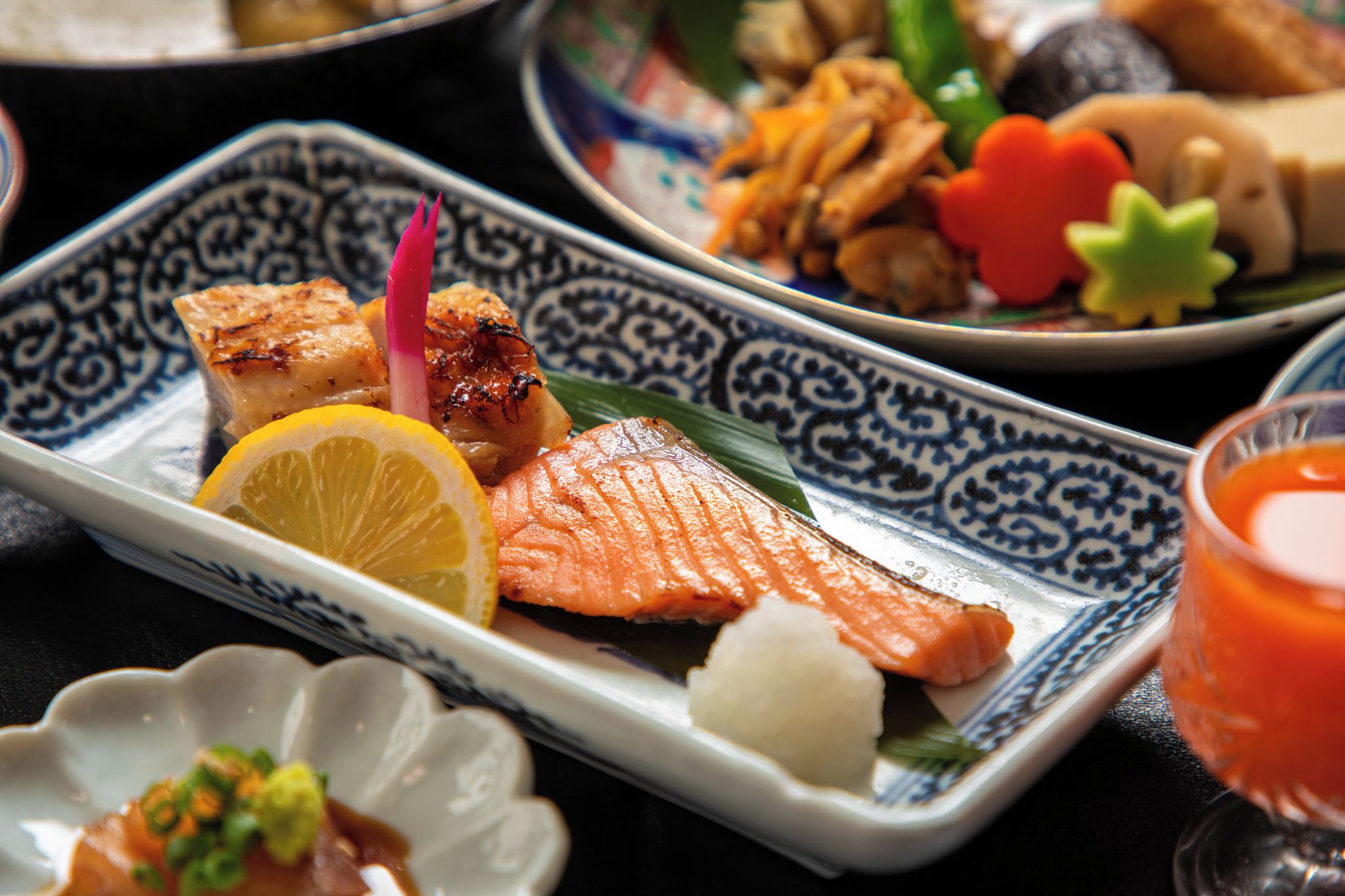 A variety of dishes including grilled salmon, vegetables, and a small bowl of soup.
