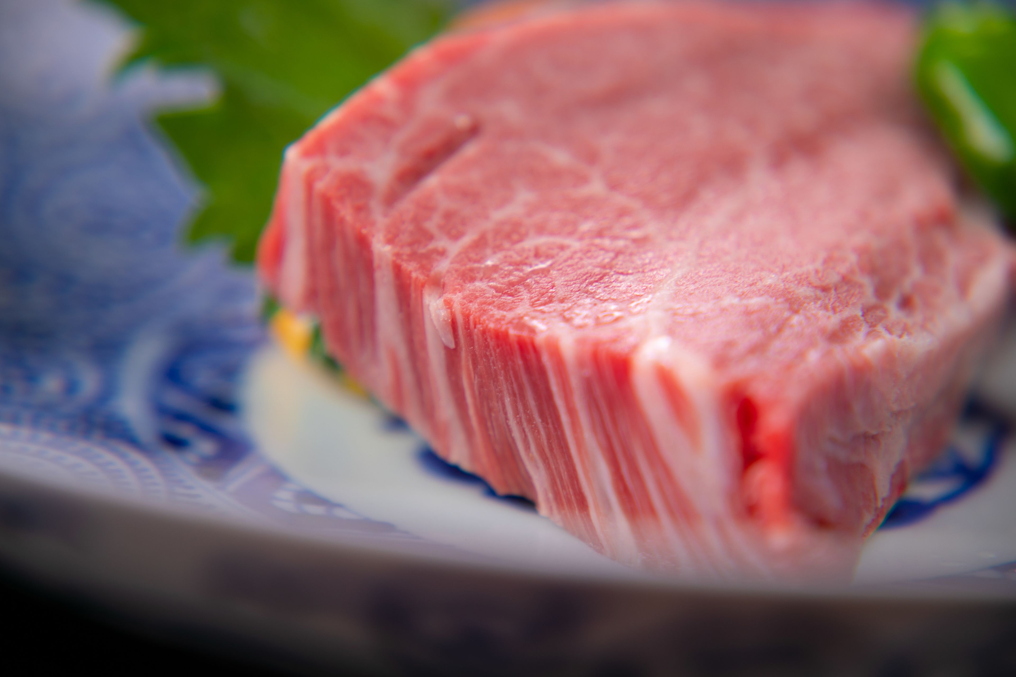 A close-up of a raw steak on a plate.