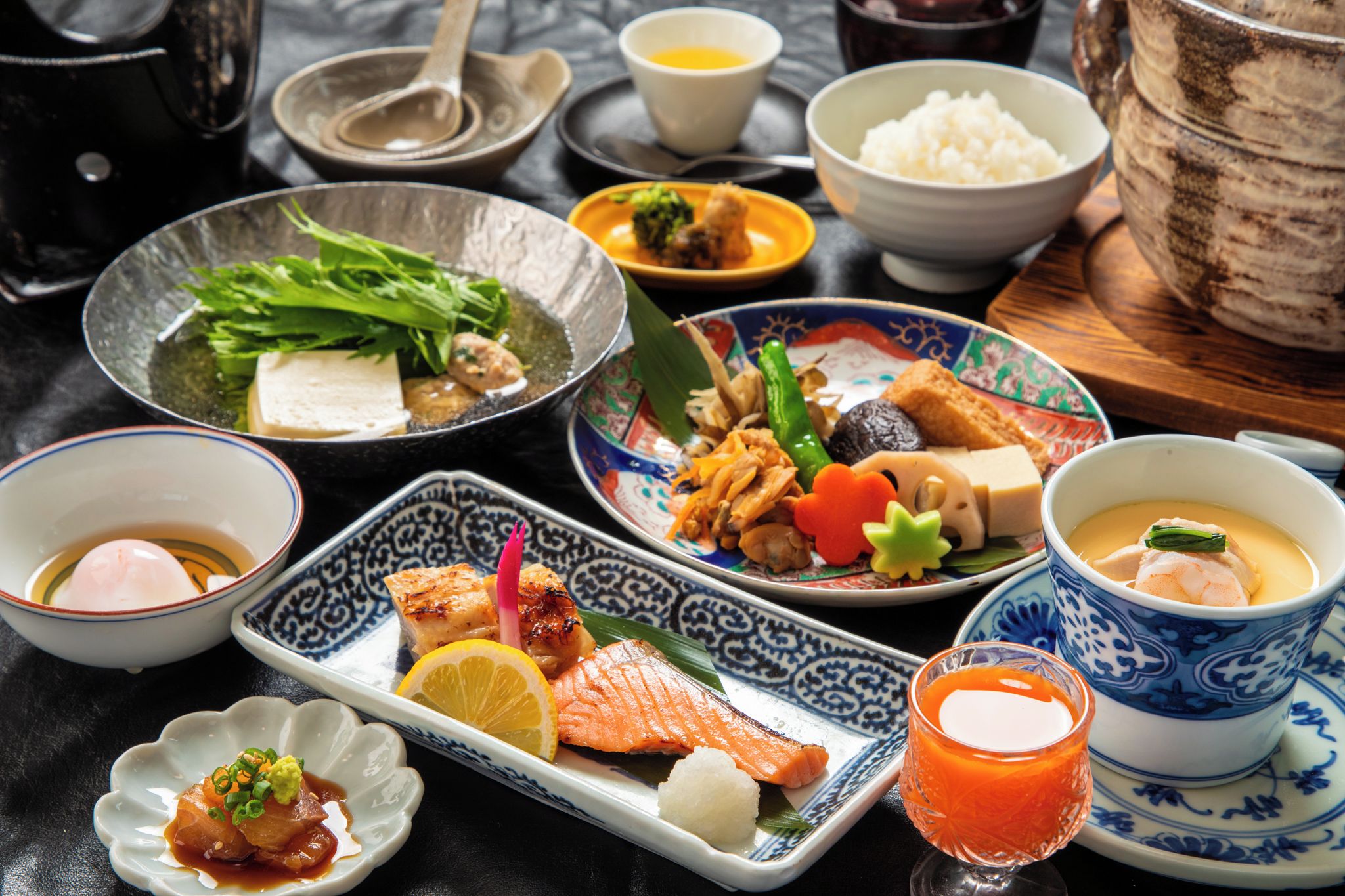 Variedad de platos japoneses, como sushi, arroz y sopa, servidos en cerámica tradicional.