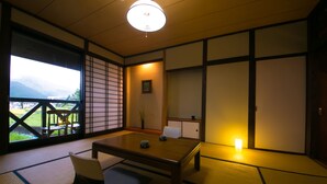Una habitación japonesa tradicional con suelo de tatami, una mesa baja y puertas correderas.