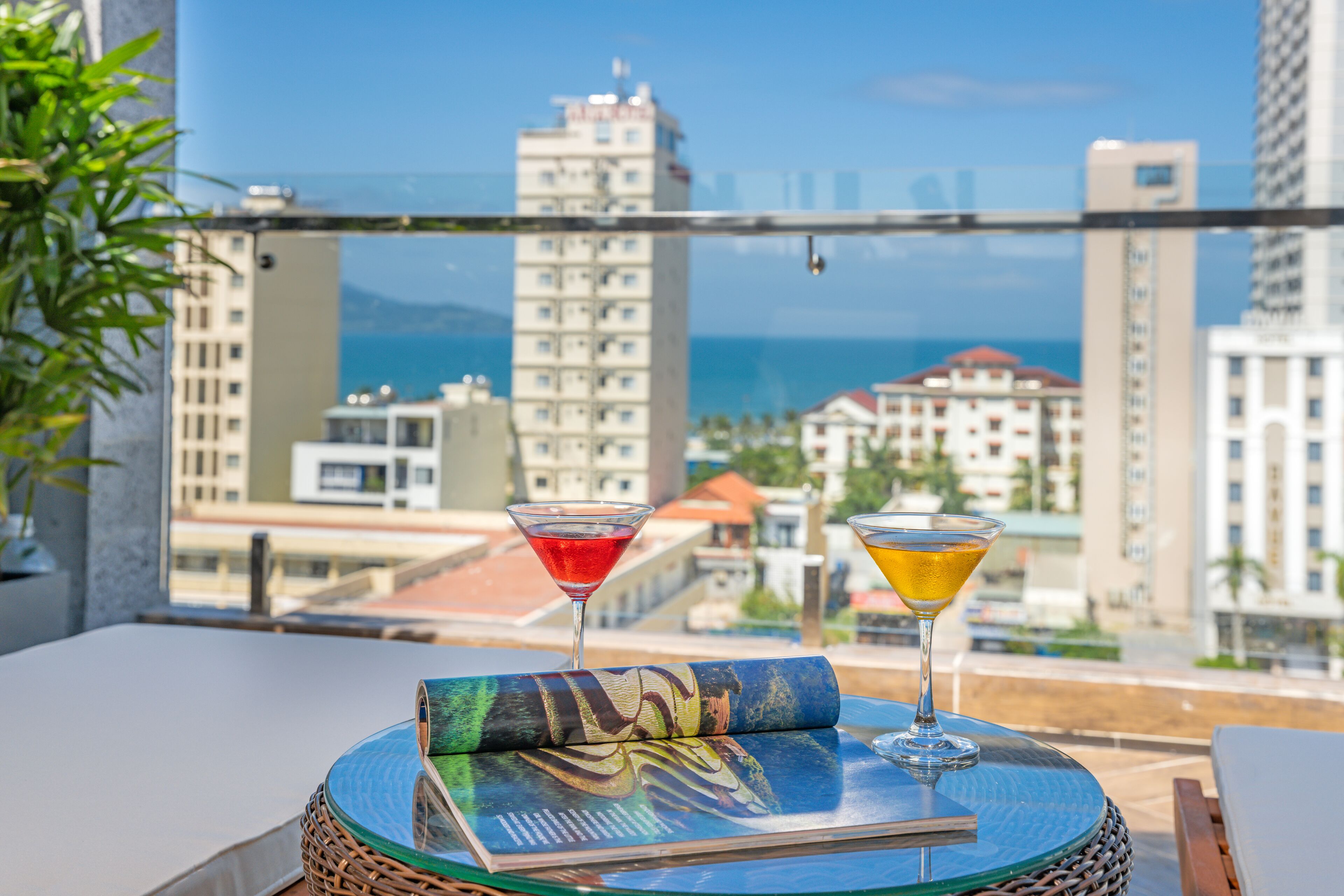 Un balcon avec vue sur la ville, deux boissons et un livre sur une table.