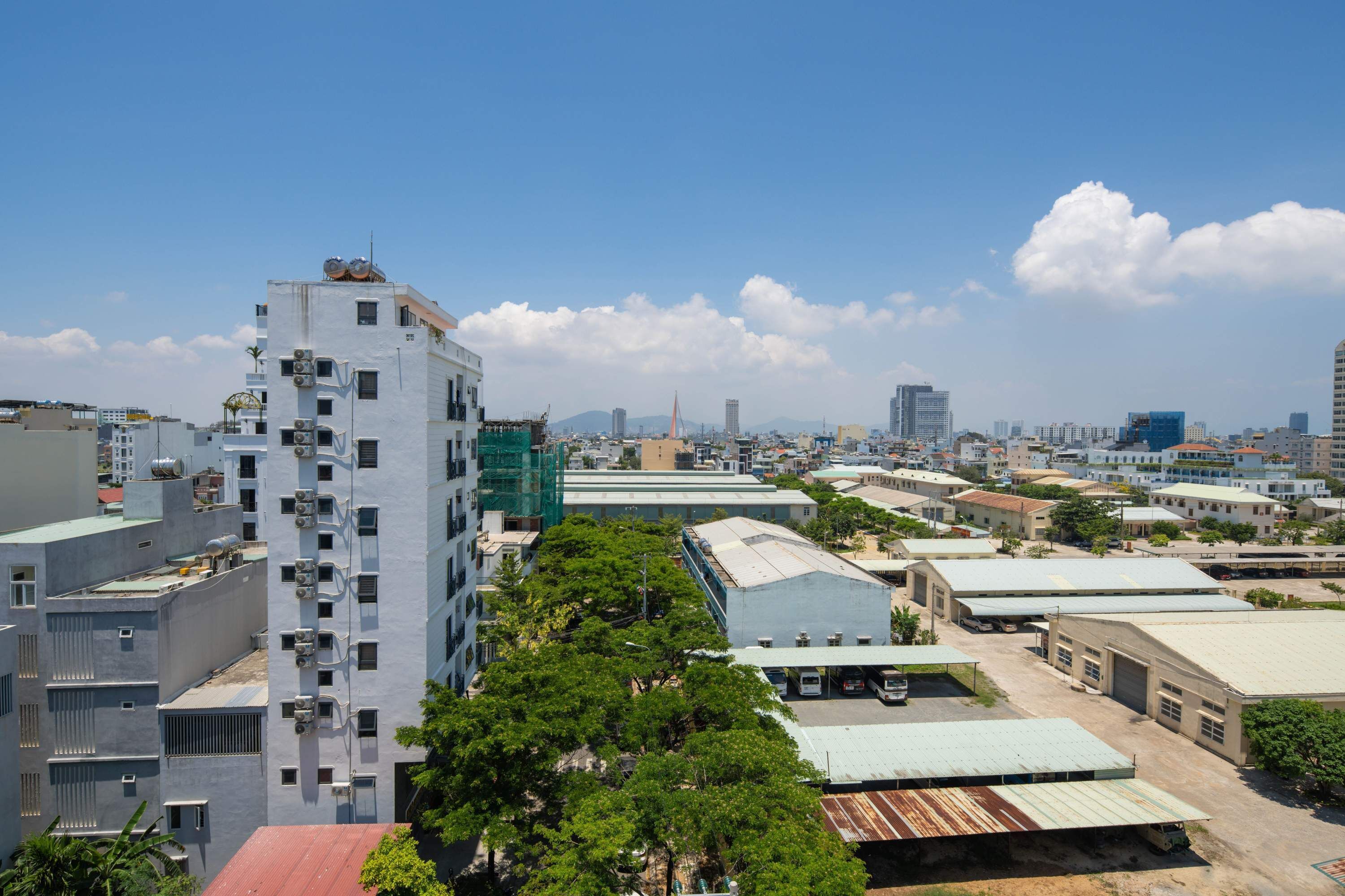 A high-rise building with multiple floors and a flat roof, surrounded by other buildings and greenery.