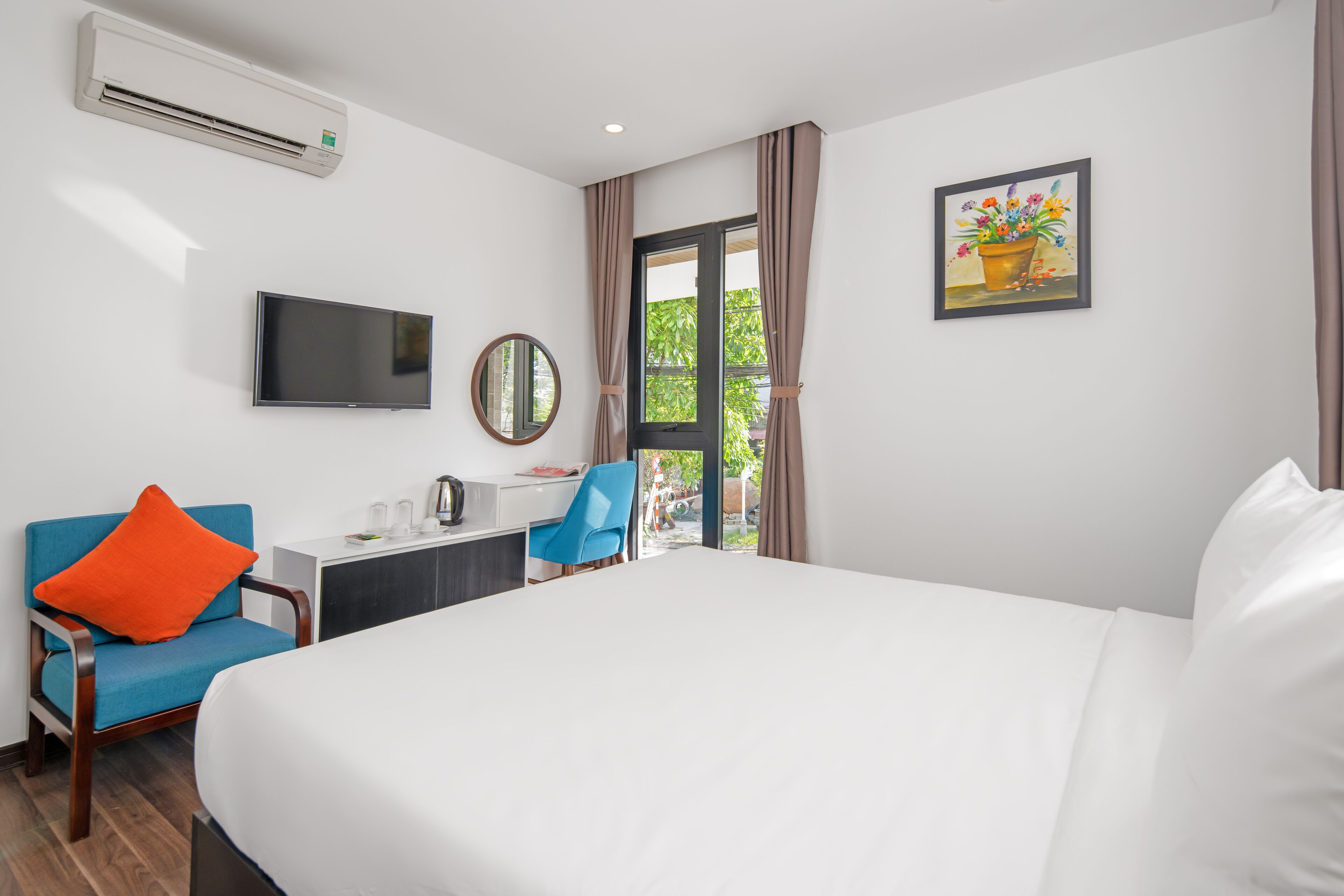 Habitación de hotel con cama, escritorio, silla, televisor y aire acondicionado.
