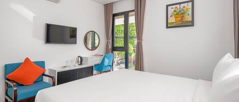 Habitación de hotel con cama, escritorio, silla, televisor y aire acondicionado.