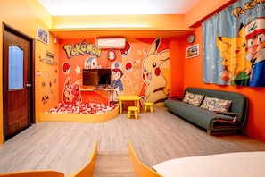 A room with a wooden floor, a sofa, a table, and a play area with balls.