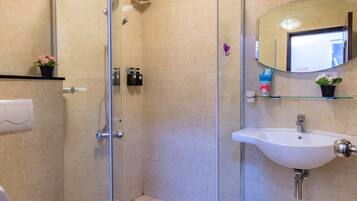 Un baño moderno con cabina de ducha de vidrio, un lavabo blanco y un inodoro.