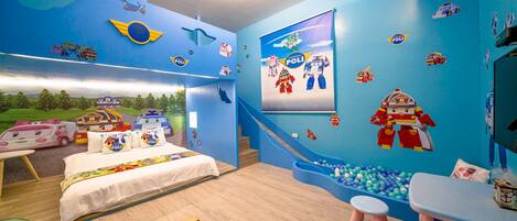 Una habitación infantil con cama, zona de juegos y decoración en la pared.