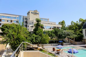 Un hotel con zona de piscina, mobiliario exterior y una escalera que conduce a la entrada.