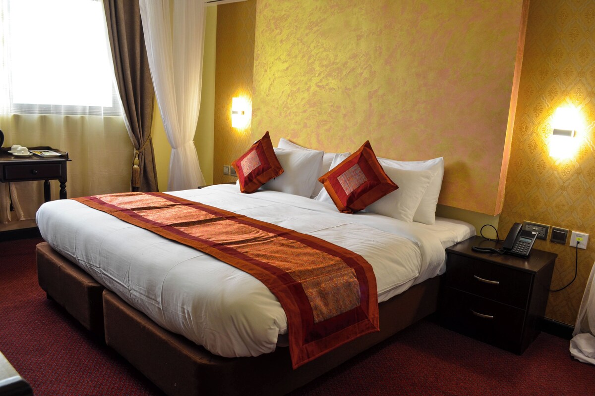 Een hotelkamer met een groot bed, een nachtkastje met een telefoon en een wandlamp.