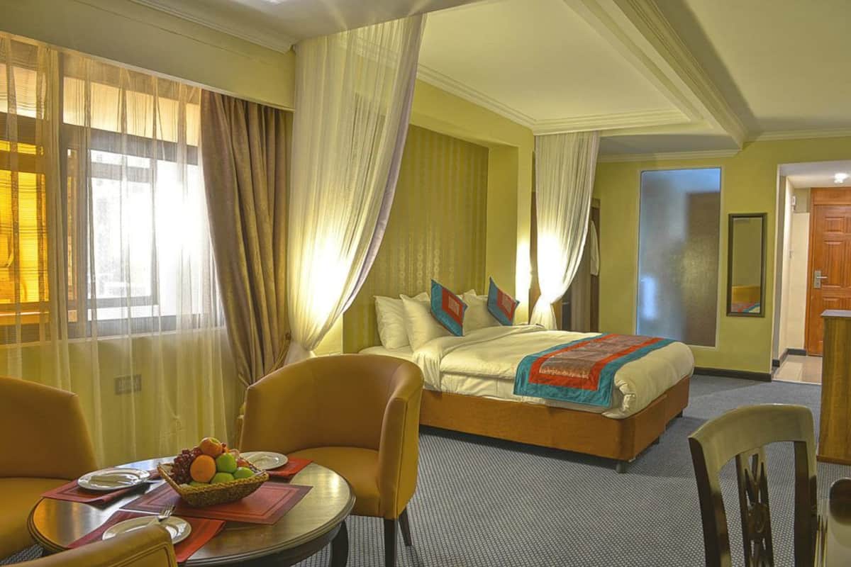 Een hotelkamer met een bed, een eettafel met stoelen en een schaal fruit.