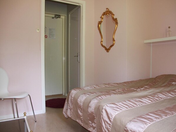 A bedroom with a bed, a chair, a door, and a mirror. - Fjällbacka Pensionat & Vandrarhem (Fjallbacka)