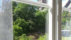 A window with a view of a church steeple and lush greenery. - Fjällbacka Pensionat & Vandrarhem (Fjallbacka)