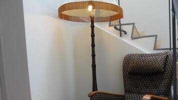 A corner of a room with a patterned chair, a tall floor lamp, and a staircase with a geometric design.