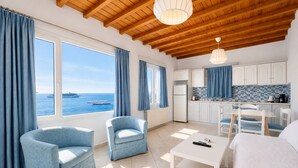 A room with a view of the sea, a kitchen, and two blue armchairs. - Villa Oceania (Mykonos)