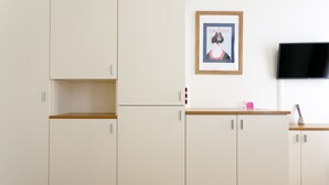 A modern kitchen with white cabinets, a wooden countertop, a framed picture, and a flat-screen TV. - Riess City Rooms - Self Check-In (Vienna)