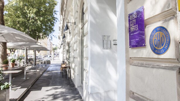 A narrow street with outdoor seating and a hotel sign. - Riess City Rooms - Self Check-In (Vienna)