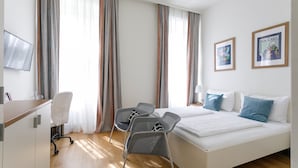 A hotel room with a bed, two chairs, a desk, a TV, and curtains. - Riess City Rooms - Self Check-In (Vienna)