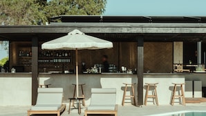 A poolside area with lounge chairs, a bar, and a covered seating area. - Asterion Suites & Spa - Designed for Adults (Platanias)