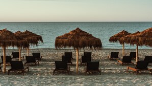 A beach with thatched umbrellas and wooden chairs aligned in rows, facing the sea. - Asterion Suites & Spa - Designed for Adults (Platanias)