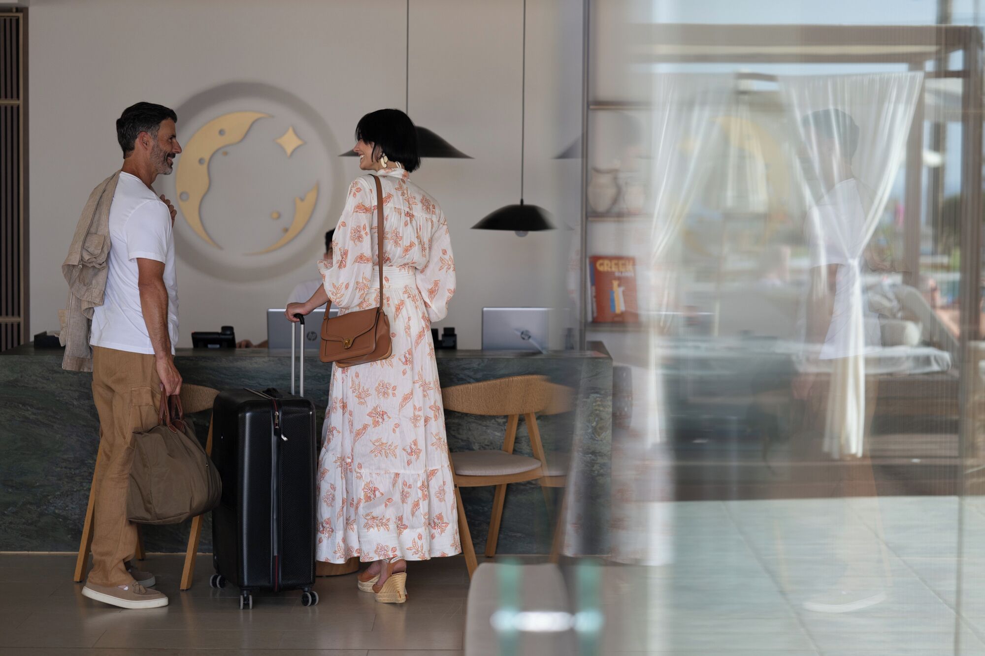 Un hombre y una mujer con equipaje en la recepción de un hotel.