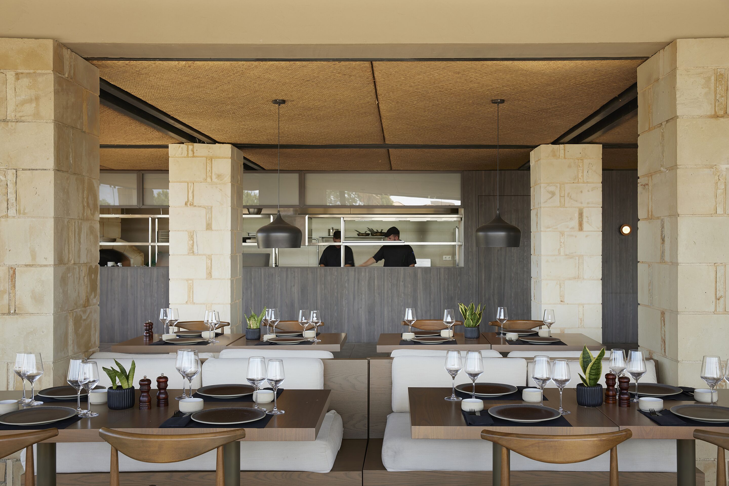 A modern restaurant with booth seating, wooden tables, and a stone accent wall.