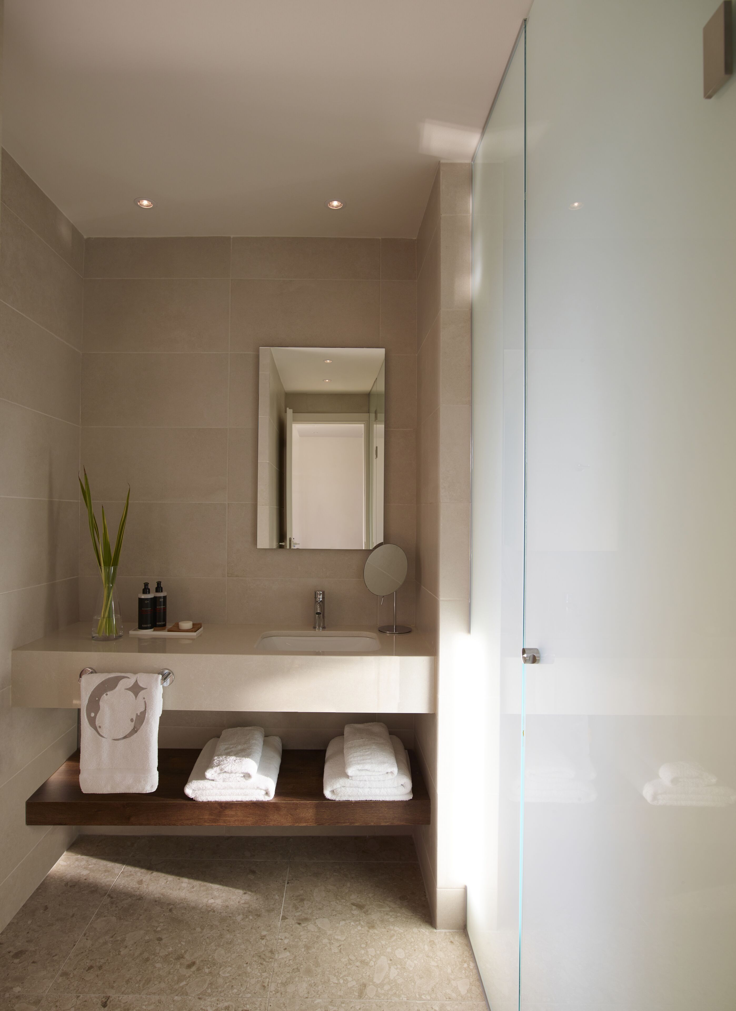 Een moderne badkamer met een grote spiegel, een wastafel en een douchecabine van glas.
