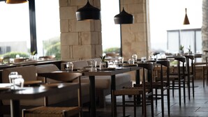 A restaurant with high tables and chairs, stone walls, and hanging pendant lights. - Asterion Suites & Spa - Designed for Adults (Platanias)