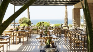 An outdoor dining area with tables and chairs, a pergola, and a view of the sea. - Asterion Suites & Spa - Designed for Adults (Platanias)