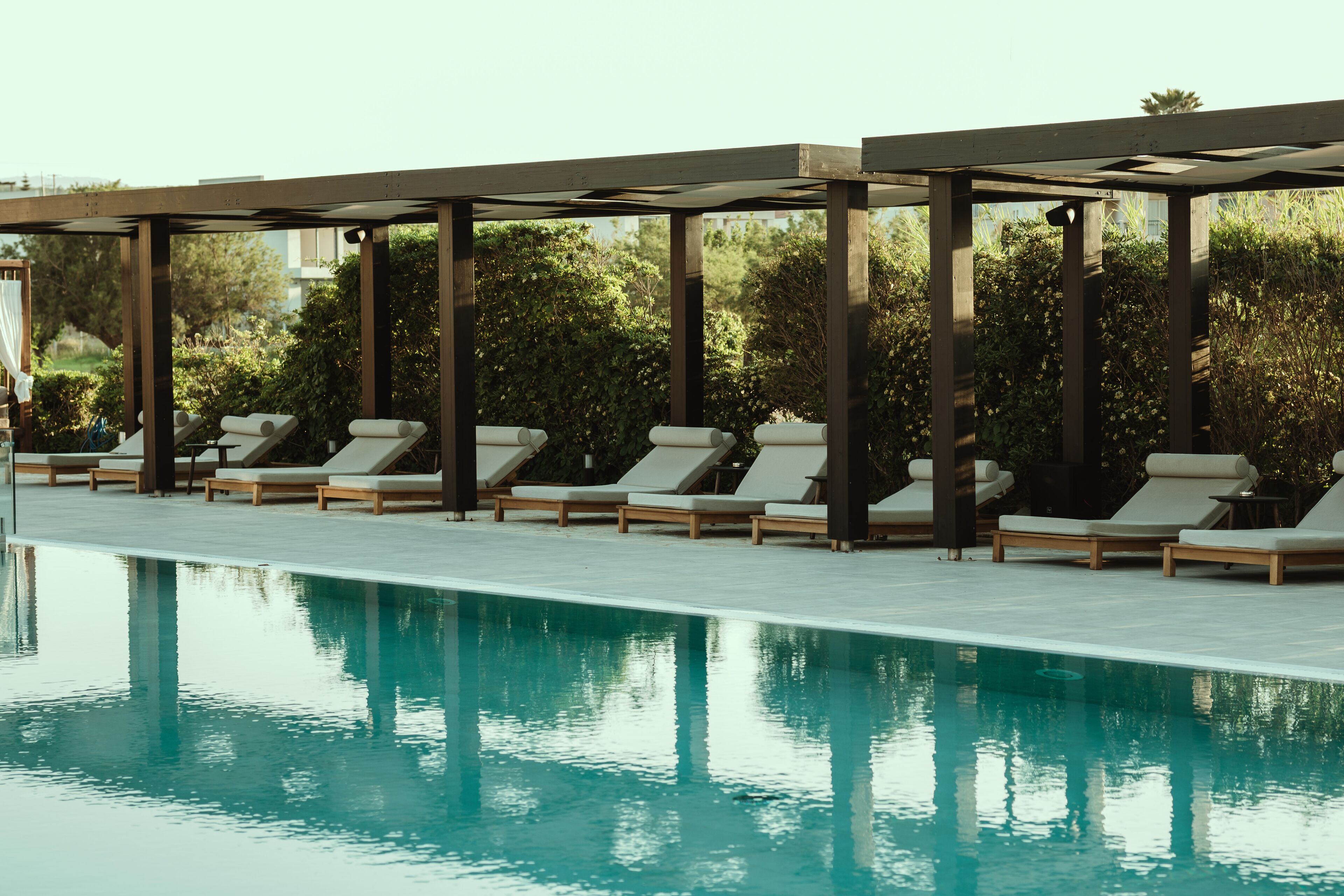 Ein Poolbereich mit Liegestühlen und einer Pergola.