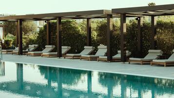 Ein Poolbereich mit Liegestühlen und einer Pergola.