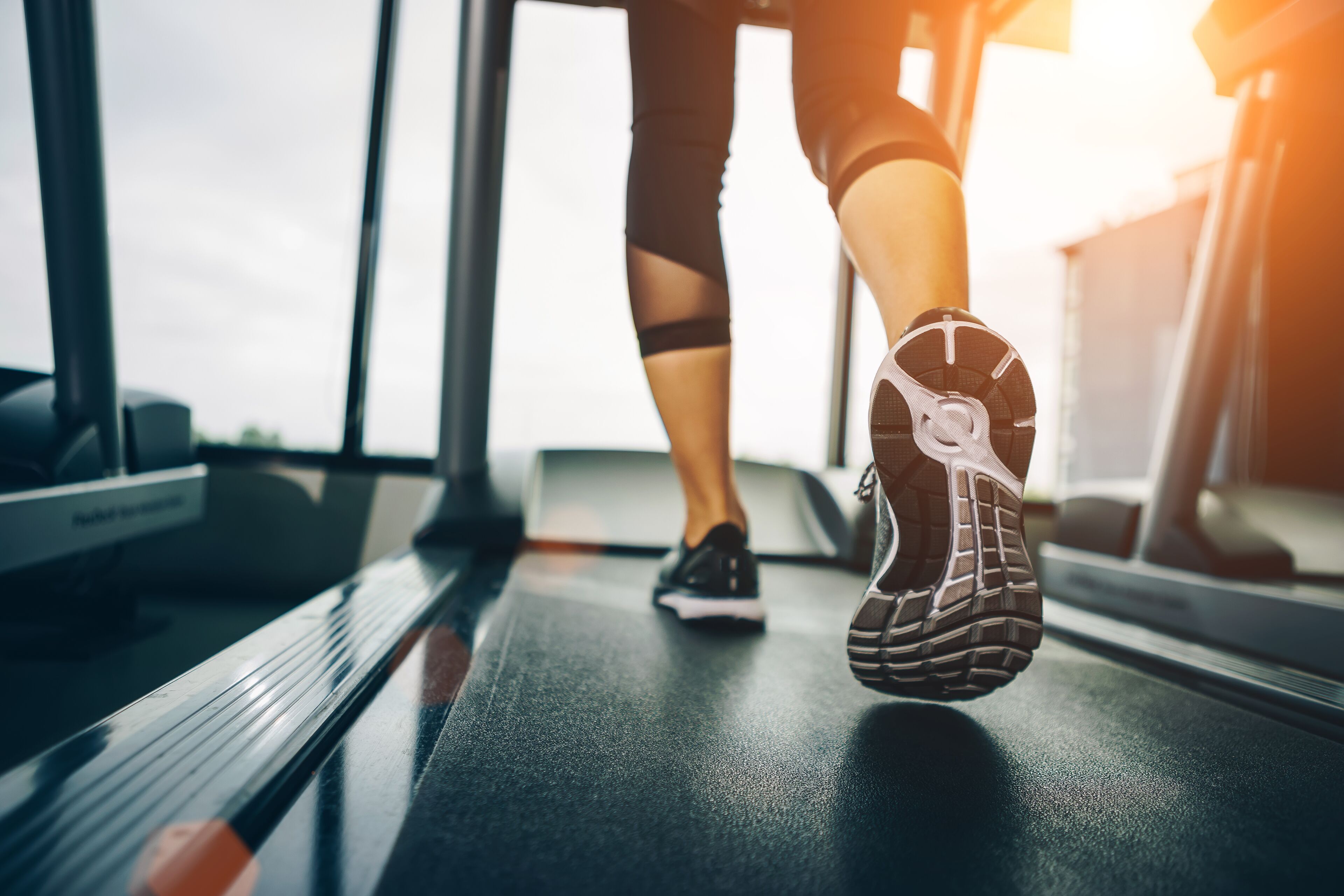 Een voet op een loopband, wat wijst op een sportschool.