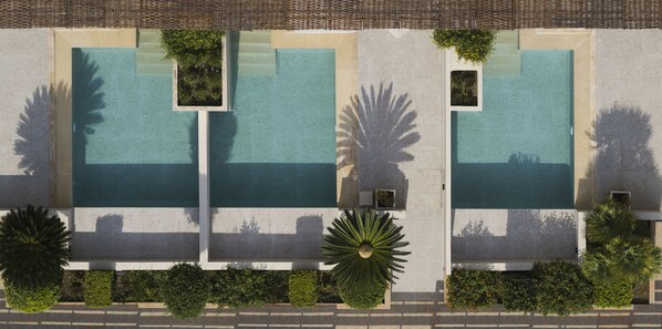 An aerial view of a hotel with three swimming pools, each with a small garden area.