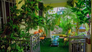 A room with a green artificial grass floor, metal railings, and several chairs. - Gahahe Hills Hotel (Bujumbura)