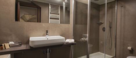 Un baño moderno con ducha de vidrio, lavamanos e inodoro.